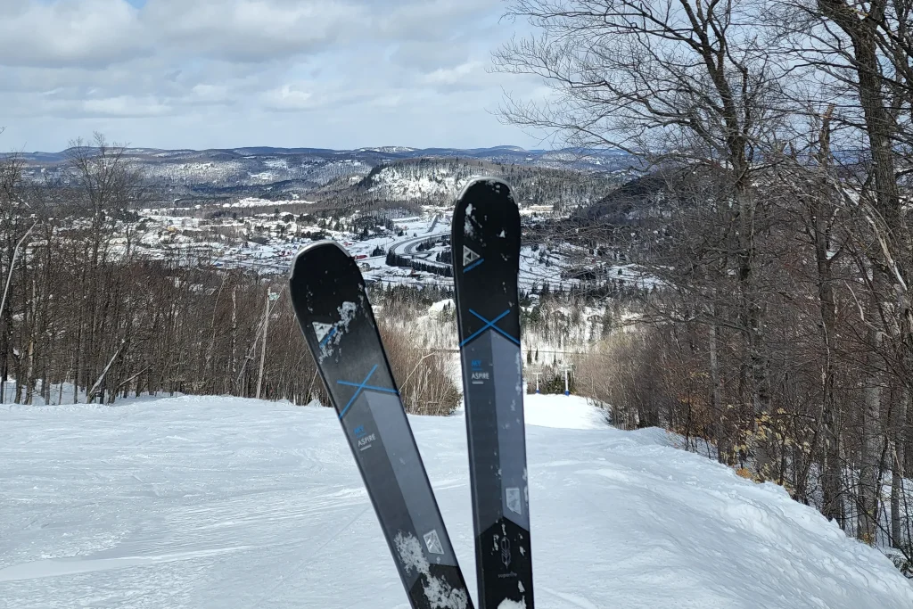 a pair of skis standing in the snow with a background village view covered in snow