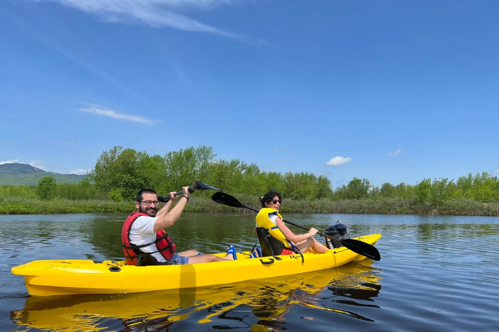 2 individuals sitting in a yellow kayak on the lake