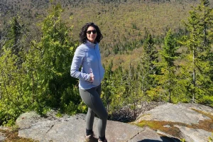 a girl standing on a rock wearing hiking clothes looking at the camera