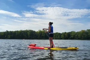a girl standing on a paddleboard in the middle of the river